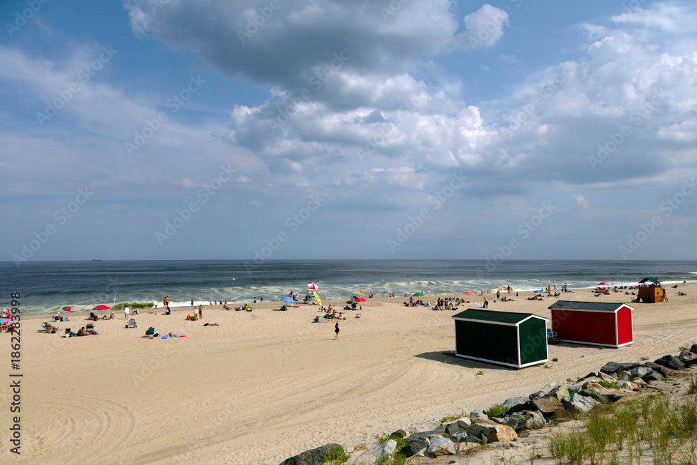 Obraz premium Bright sunlit beach scene with colorful cabins and people