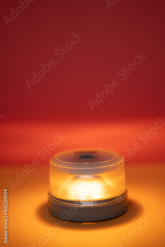 v16 beacon Portable illuminating signal light glowing amber against a warm red and orange background