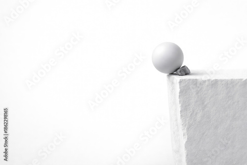 A white ball on the edge of a block with a stone. Space for text.
