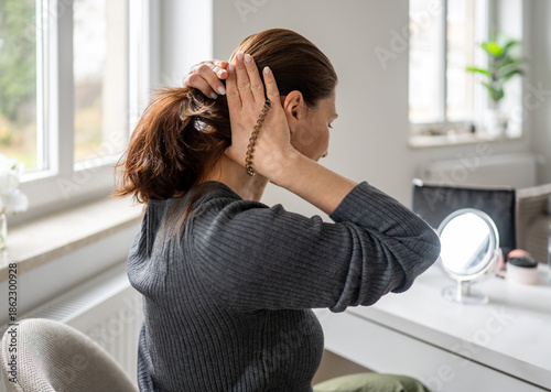 Vászonkép Woman Tying Hair Into Ponytail While Sitting At Dressing Table