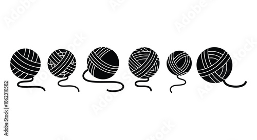 A series of black and white yarn balls with trailing ends arranged in a linear fashion