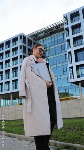Wallpaper Mural Vertical screen confident young woman holding laptop and documents outside modern office building after finishing important work showing relief pride and success Torontodigital.ca