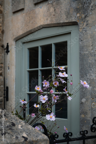 Stone cottage window with pink flowers in the Cotswolds