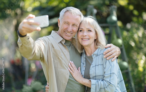 Photography Happy elderly couple spending time in their garden together, taking selfies and smiling at cellphone camera