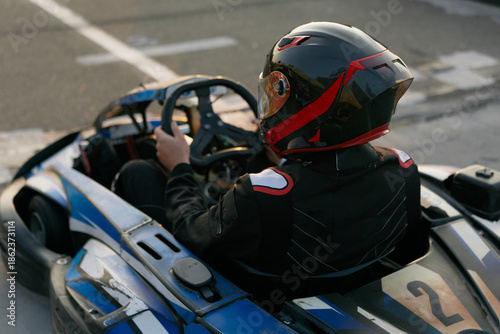 Foto A focused go-kart driver in a sleek helmet prepares to race on a track