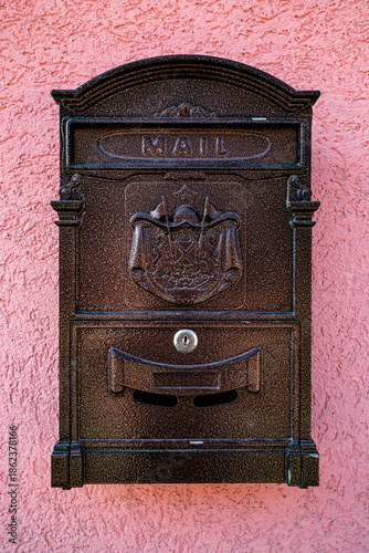 An iron mailbox on the wall of a building on the street