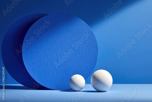 Blue circles & spheres cast shadows. Minimalist geometric design. Light & shadow play