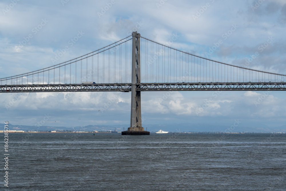Fototapeta premium A view of San Francisco looking toward the impressive Bay Bridge leading to Oakland, set beneath an overcast sky that adds a moody, urban atmosphere.