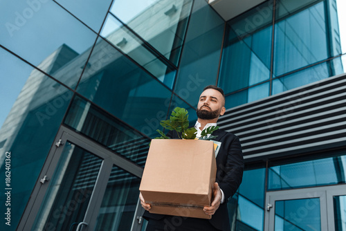 Wallpaper Mural Fired depressed male office worker with box of personal stuff walking outdoor, lost job and left without money. Businessman standing near glass office building. Unemployment concept Torontodigital.ca