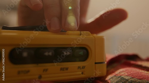 Woman pressing play on portable cassette player - Listing to music laying on bed