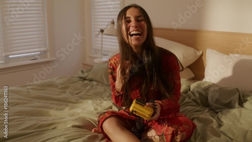 Dreamcore woman laughing as she takes off headphones listening to music on bed