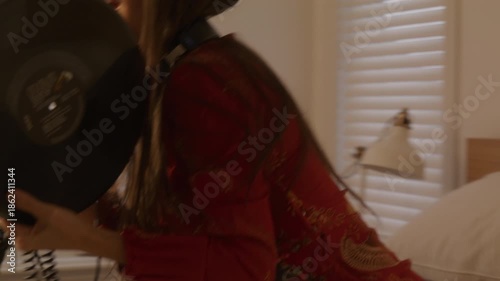 Dreamcore woman gets up to put a vinyl record on the player - music listening with headphones