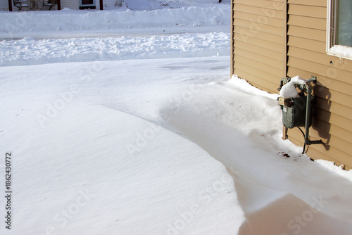 A gas meter in on the side of the house in the snow