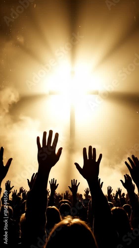 A silhouette of a crowd with hands raised in supplication towards a bright, illuminated cross against a smoky, golden sky, evoking a sense of spiritual awe.