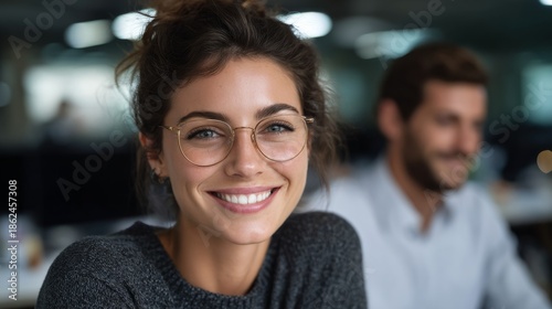 A Portrait of a smiling woman wearing glasses in an office environment, exuding confidence and approachability