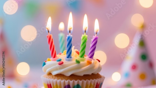 A colorful cupcake with lit candles in a festive setting