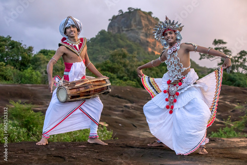 SIGIRIYA, SRI LANKA - DECEMBER 04, 2025 : A Gatabera Player (Getaberakaruwo) and a Ves Dancer or Up Country Dancer perform in front of Sigiriya Rock in Sri Lanka.