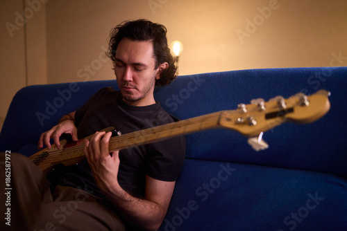 Obraz na plátně Musician working in cozy studio, Casual musician practicing bass with effects an