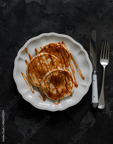 Pancakes with caramel sauce - delicious dessert, breakfast on a dark background, top view