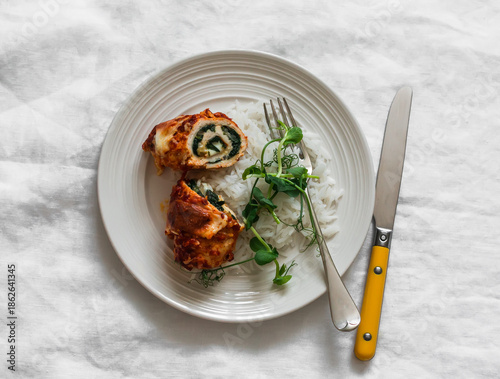 Chicken rolls stuffed with spinach, mozzarella and rice on a light background, top view