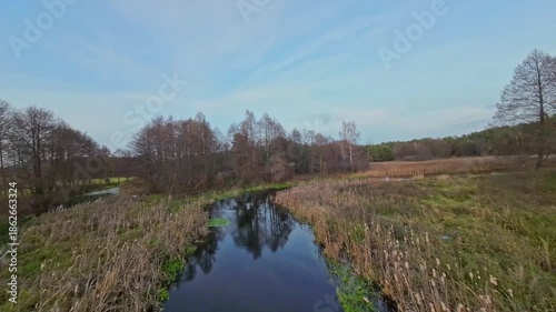 A low and fast drone flight over a river and meadow.