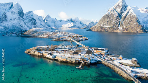 Принти на полотні Aerial view of Sakrisøy in the Lofoten Islands, where bright yellow rorbuer fishing cabins stand out against snowy winter landscapes and striking turquoise-blue Arctic waters