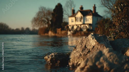 Picturesque view of a riverside dwelling from a rocky shore, with calm water and soft light, evoking tranquility and timeless charm.