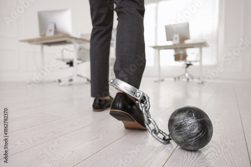 Photos Businessman with metal ball and chain on his leg in office, closeup