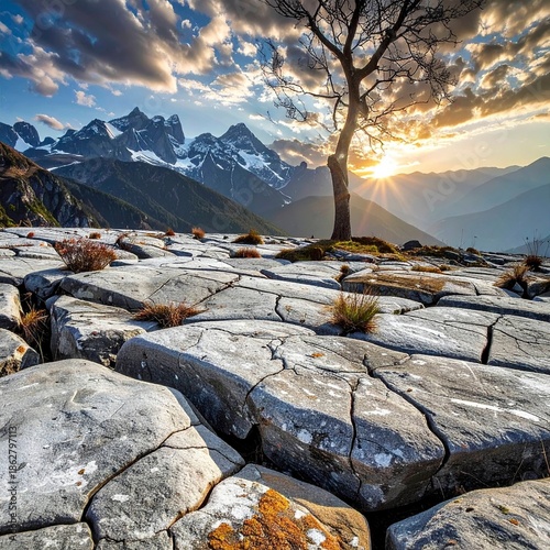 Dramatic landscape of mountain range under cloudy sky with sun rays and rock surface