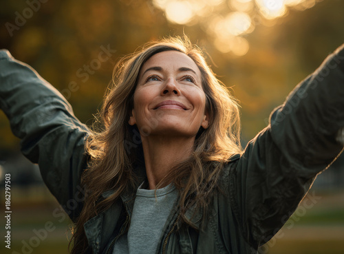 Mujer mayor senior de mas de 50 años relajandose en un bosque sonriendo haciendo estiramientos con los brazos durante una puesta de sol
