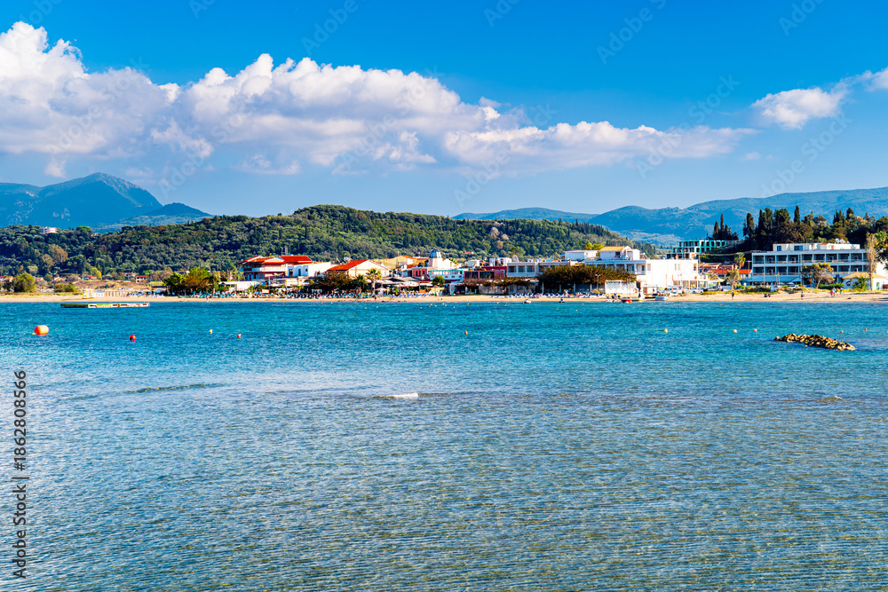 Fototapeta premium Sidari beach with tourists, mountainous landscape of Corfu in background, Greek paradise.
