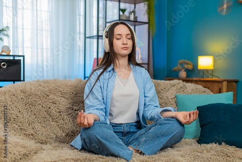 Obraz na plátně Young pretty woman at home calmly relaxing with closed eyes, quietly breathing listening meditation music in headphones