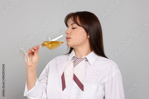 Fotografija Professional sommelier tasting white wine on light grey background