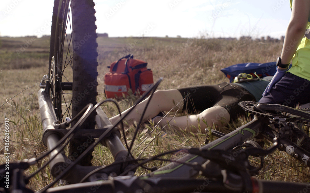 Obraz premium Cyclist injured in the middle of the countryside receives medical attention