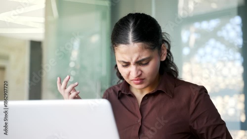 Frustrated angry businesswoman having problems with software or service on laptop sitting at workplace in business office. Disappointed female worker has issue with task on computer. Close up