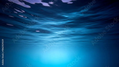 Underwater scene with sunlight shining through the waves on a serene ocean surface from a low angle viewpoint