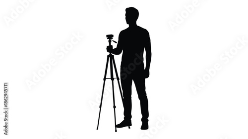 Silhouette of a man operating a camera on a tripod stand