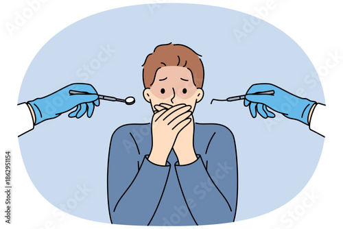 Man suffering from dentophobia closes mouth and stands near hands with dental devices. Guy is afraid of doctors at dental clinic, and feels panic, not allowing caries to be treated