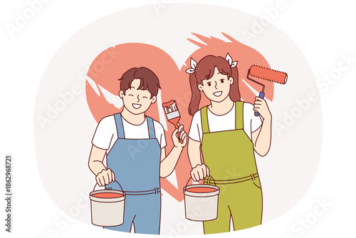 Boy and girl painted heart on wall using bucket of paint and roller with brush. Heart symbolizing love or kindness with charity, behind happy teenage children dreaming of becoming artists.