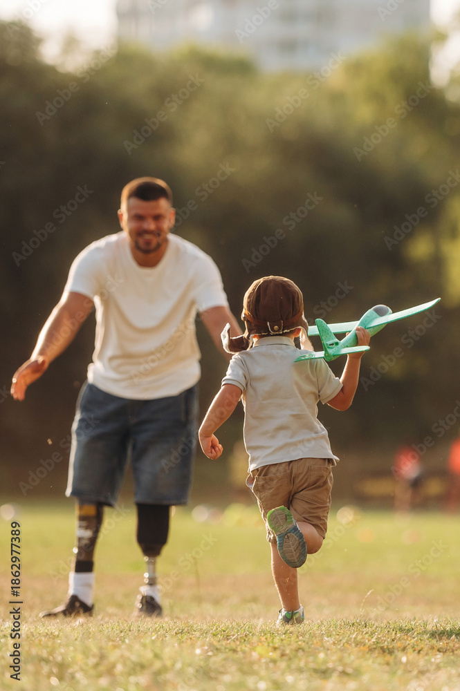 Obraz premium Bright sunlight, illuminated by it. The amputee father is with his son on the field
