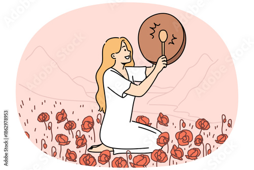 Woman shaman with drum sits in poppy field and plays ethnic musical instrument to bring about rain. Girl shaman observes mystical traditions of calling gods on days of spring equinox