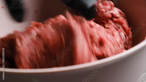 Ultra close up of a chefs hand in black culinary gloves mixing bright red beef mince for cooking food. Beef or lamb minced meat in Muslim national cuisine. Halal guaranteed with no pork.