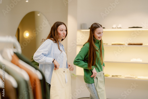 Foto Two friends are trying on different pants in a bright, contemporary clothing store