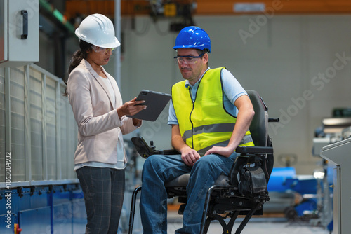 Smiling Indian female factory manager showing the production line to a man worker with disability, and congratulating him on a new job.