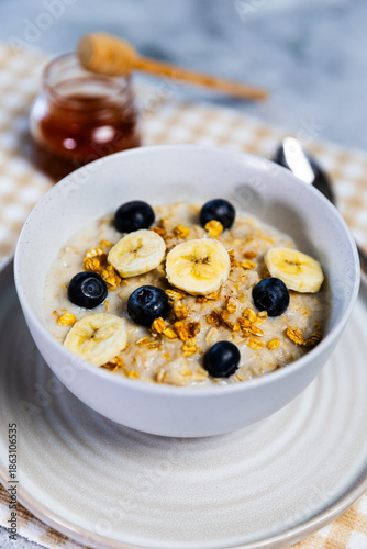 Healthy oatmeal bowl with banana, blueberries and honey drizzle