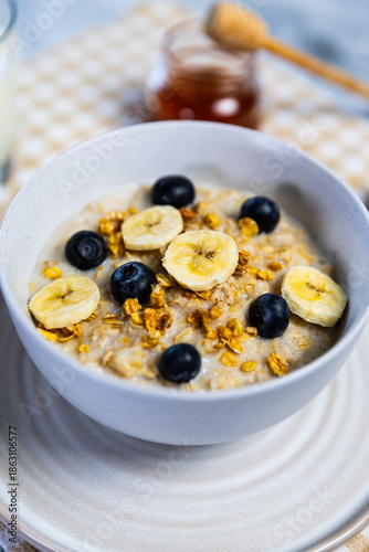 Healthy oatmeal bowl with banana, blueberries and honey drizzle