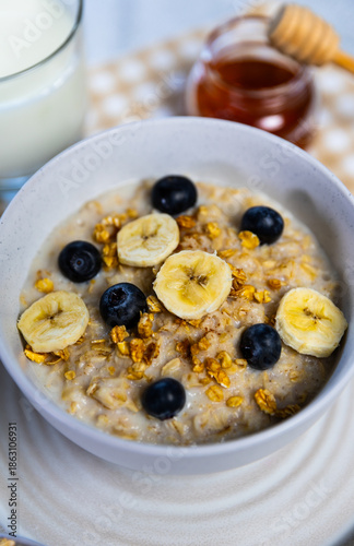 Healthy oatmeal bowl with banana, blueberries and honey drizzle