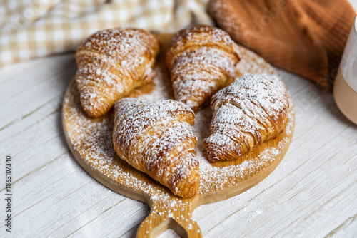 Fresh butter croissants on wooden board with coffee