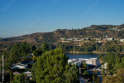 Los Angeles, USA - October 18, 2025 - Hollywood Reservoir dam and city skyline view with lush green trees and palm trees