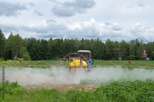 A tractor sprays fresh potatoes with pesticides. This pest control process is essential for growing and protecting plants
